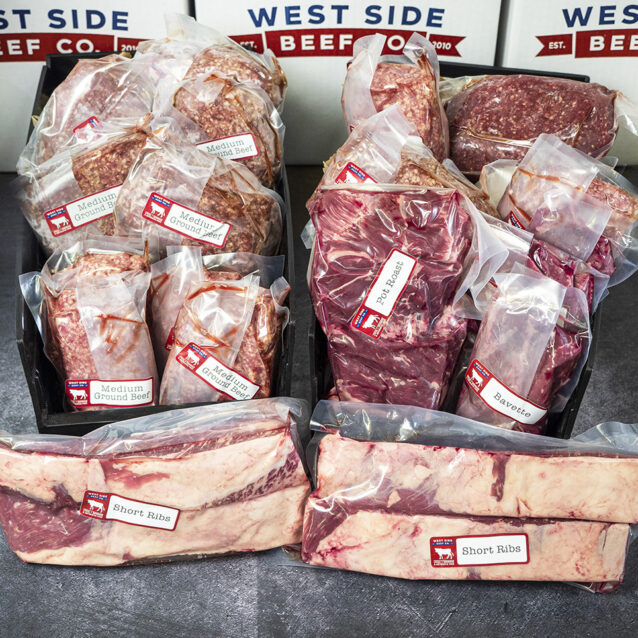 Assorted packaged beef cuts and ground beef in trays, with short ribs placed in front.