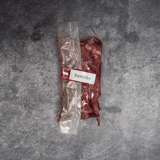 Bavette steak vacuum-sealed in clear packaging with label on a gray surface.
