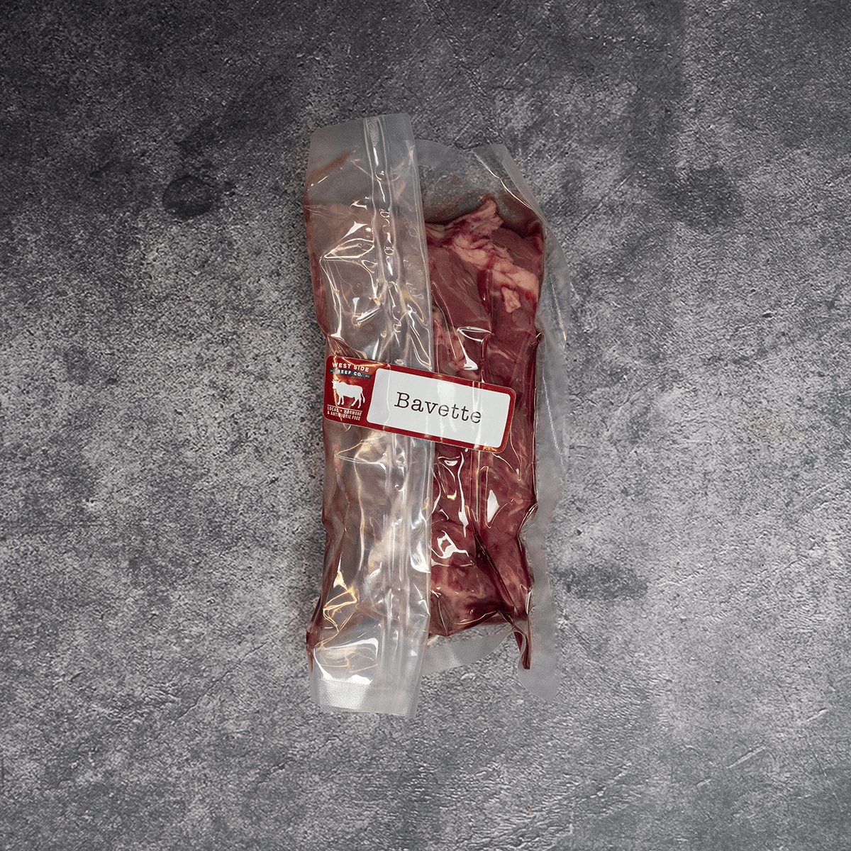 Bavette steak vacuum-sealed in clear packaging with label on a gray surface.