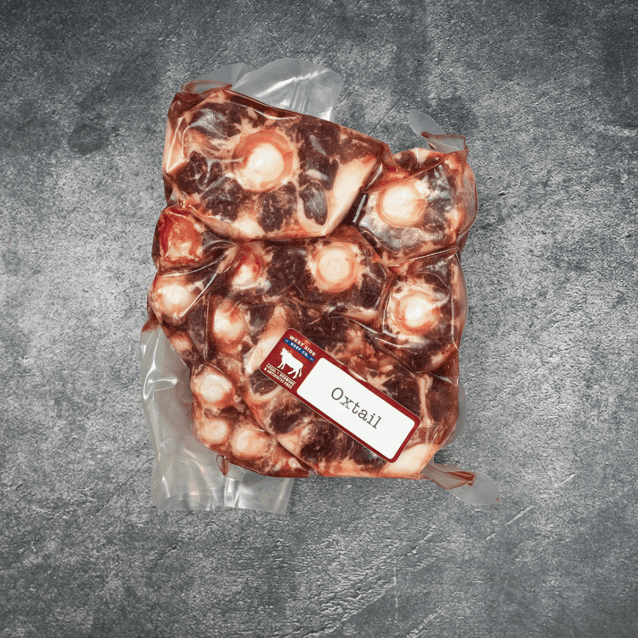Vacuum-sealed package of cut oxtail pieces with an "Oxtail" label on a gray textured background.