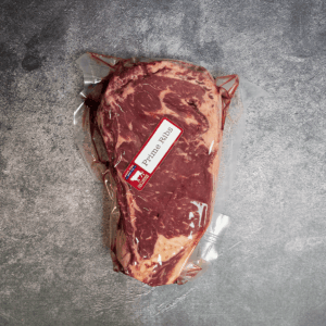 Vacuum-sealed prime rib roast with a "Prime Rib" label on a gray textured surface.