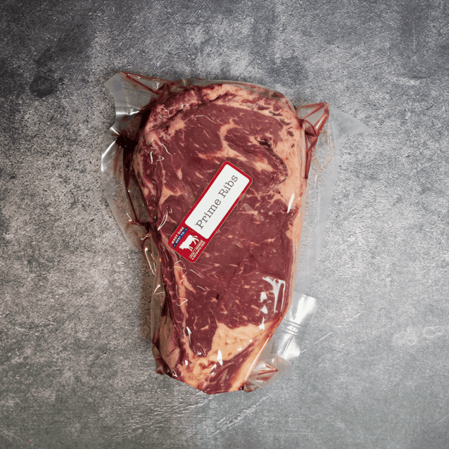 Vacuum-sealed prime rib roast with a "Prime Rib" label on a gray textured surface.