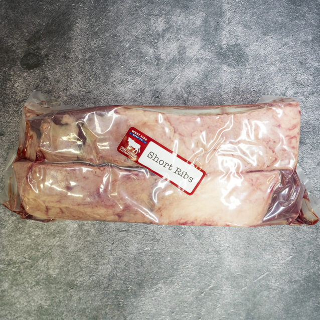 Vacuum-sealed short ribs with a "Short Ribs" label on a gray textured surface.