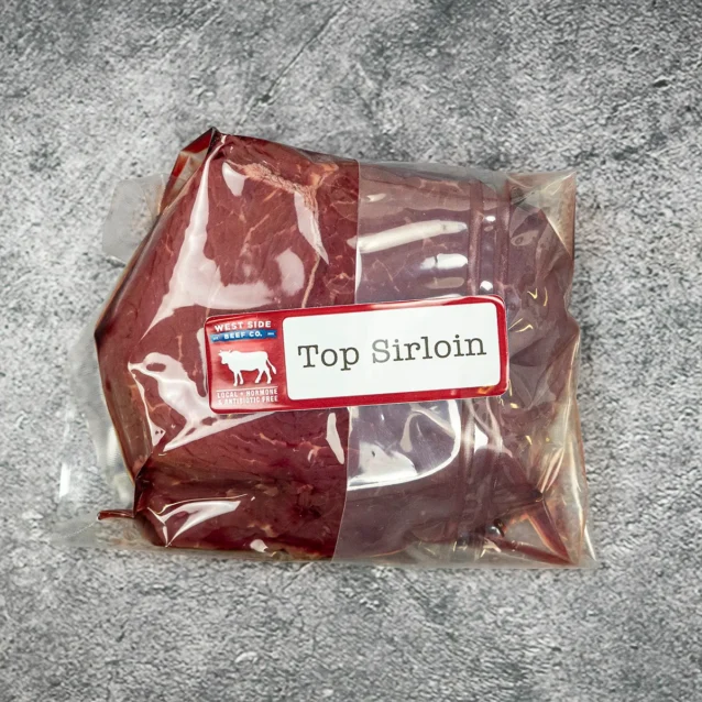 Vacuum-sealed top sirloin cut from West Side Beef Co. on a gray surface.