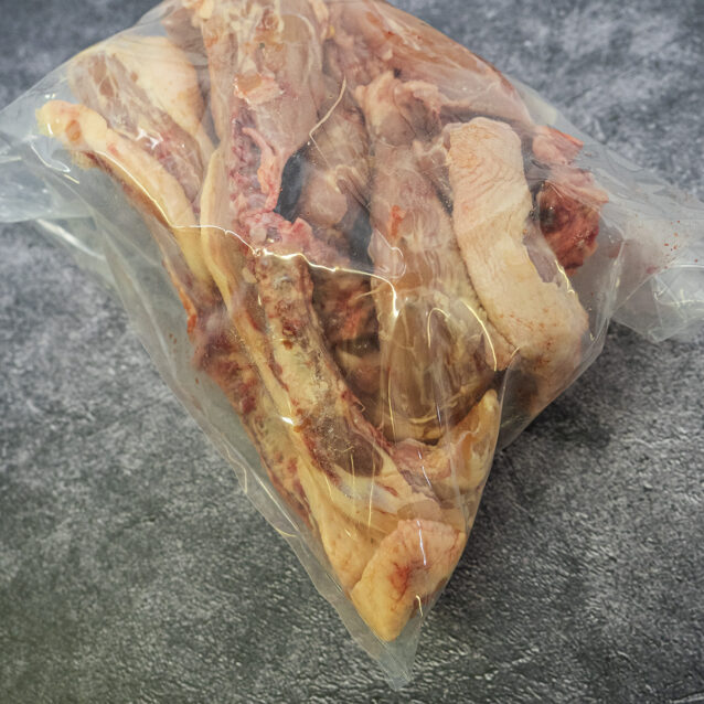 Bag of chicken bones on a gray textured surface.