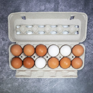Open carton of 12 brown and white eggs on a gray textured surface.
