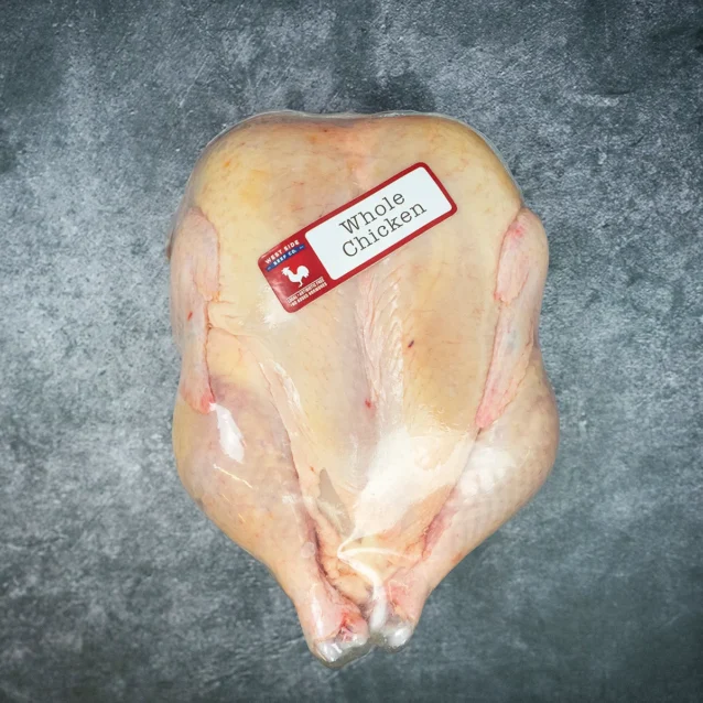 Whole raw chicken with label on a textured gray surface.