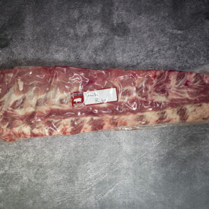 Vacuum-sealed rack of pork back ribs on a gray textured surface.