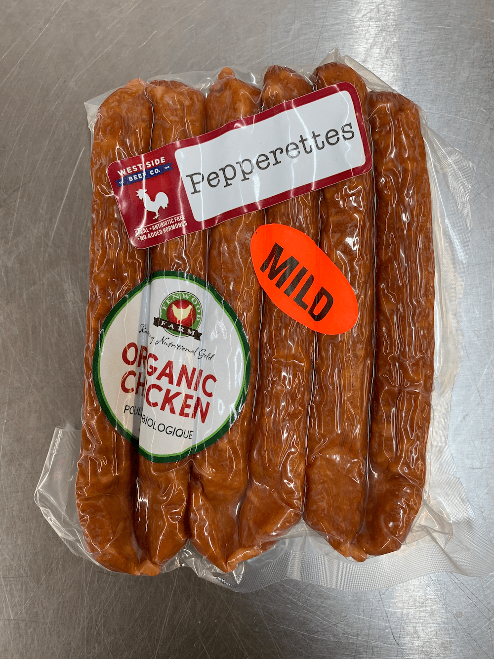 Vacuum-sealed pack of chicken pepperettes with "Pepperettes," "Organic Chicken," and "Mild" labels on a metal surface.