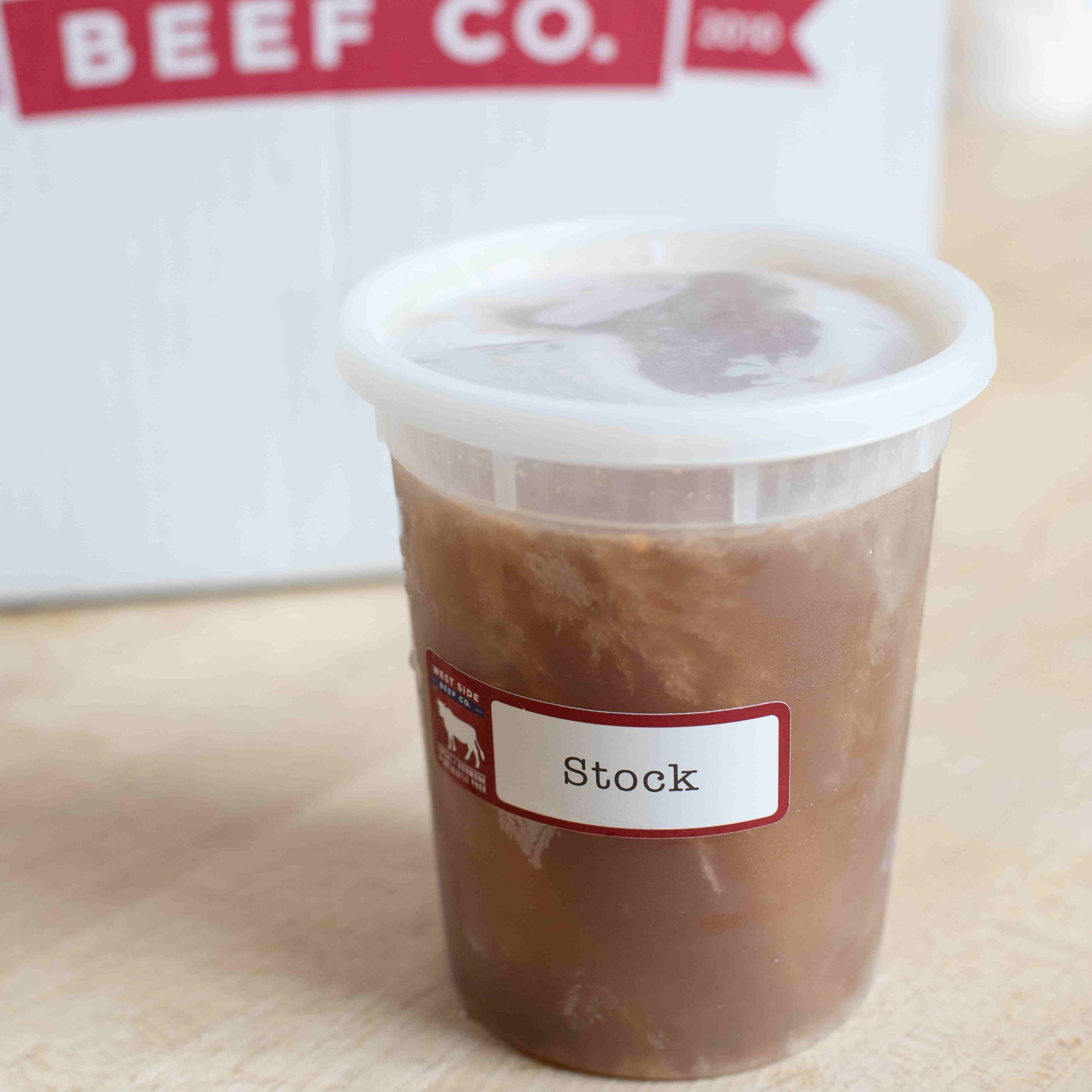 Container of prepared beef stock with a labeled lid on a countertop.