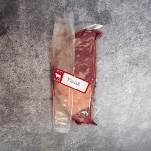 Flank steak vacuum-sealed in clear packaging with label on a gray surface.