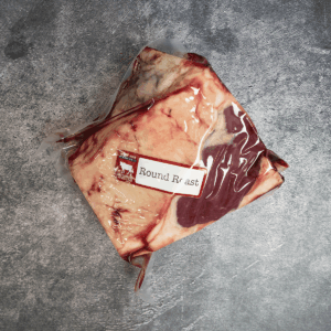 Vacuum-sealed beef round roast with visible fat layer and label.