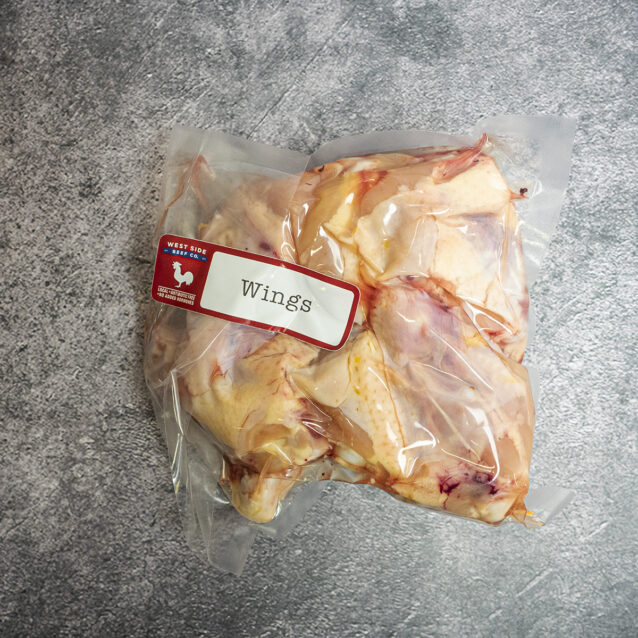 Vacuum-sealed package of raw chicken wings with skin on, labeled and placed on a gray surface.