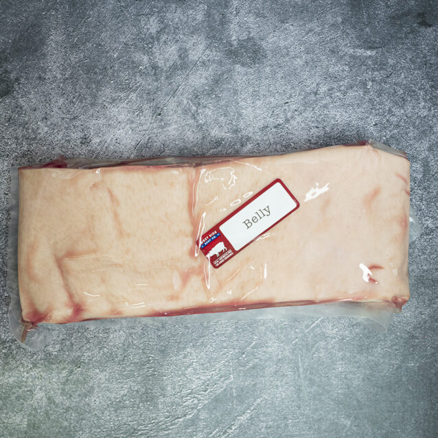 Vacuum-sealed slab of pork belly with skin and fat layer, labeled and placed on a gray surface.