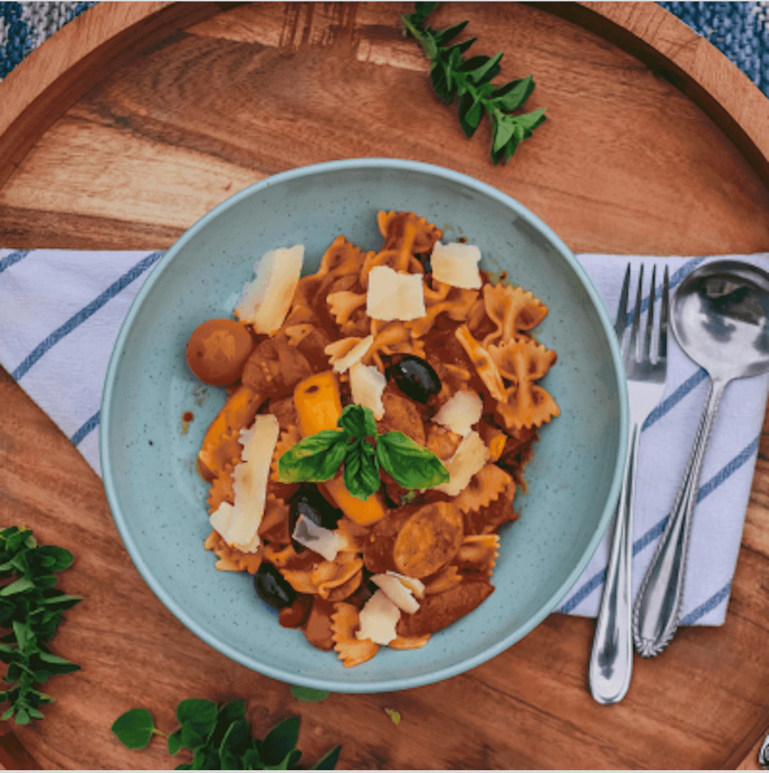 Spicy Sausage Peppers Pasta Bowl of pasta with sliced sausage, peppers, tomato sauce, and shaved cheese.