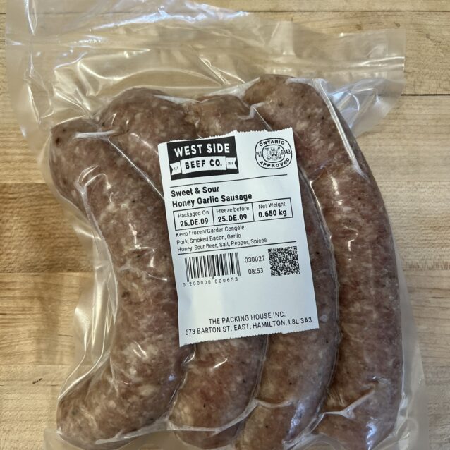Vacuum-sealed honey garlic sausages from West Side Beef Co. on a wooden surface.