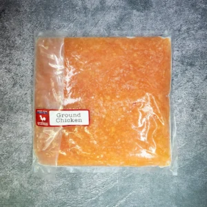 Vacuum-sealed ground chicken pack from West Side Beef Co. on a gray textured surface.