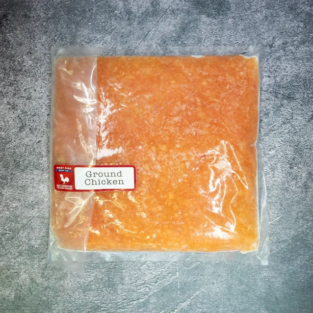 Vacuum-sealed ground chicken pack from West Side Beef Co. on a gray textured surface.