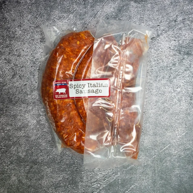 Close-up of vacuum-sealed spicy Italian sausage from West Side Beef Co. on a gray surface.