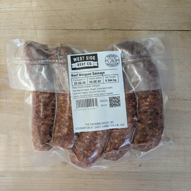 Vacuum-sealed beef merguez sausages from West Side Beef Co. on a wooden surface.