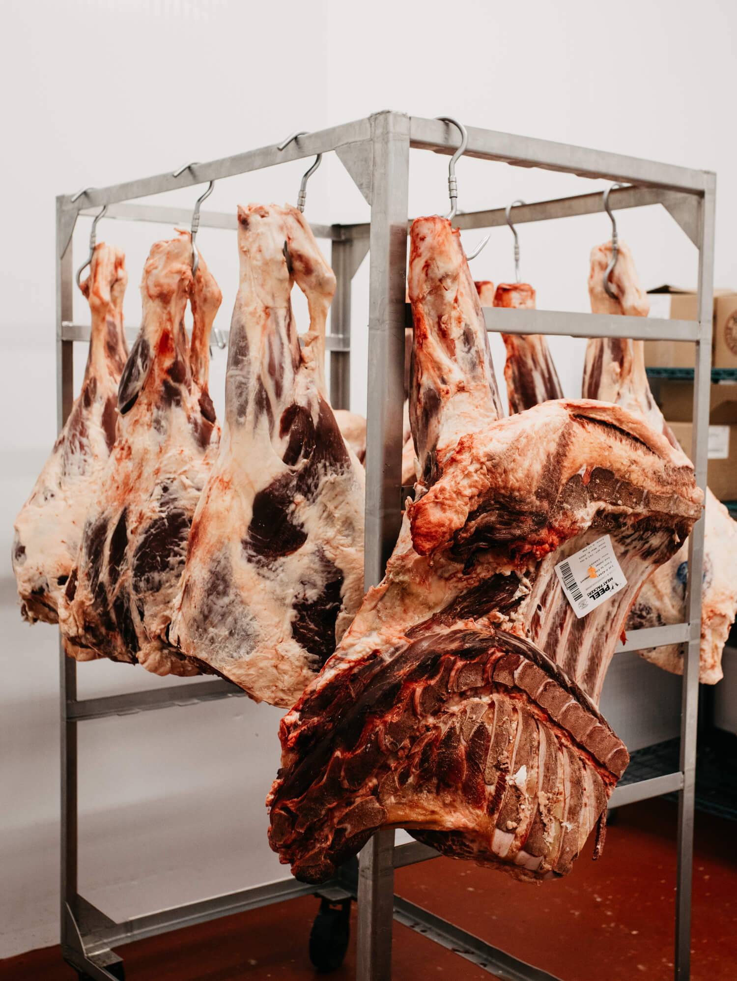 Large cuts of meat hanging on hooks from a metal rack.